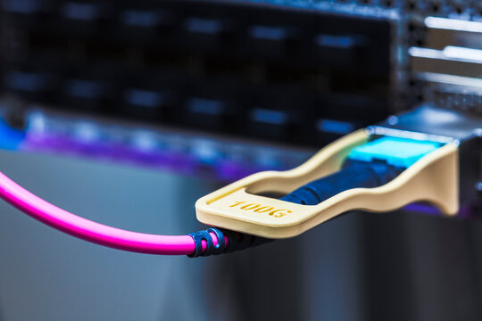Close up of a 100Gbit network transceiver with a patch cable inserted into a switch, high speed broadband networking, data transmission, telecommunications infrastructure, and modern internet connecti