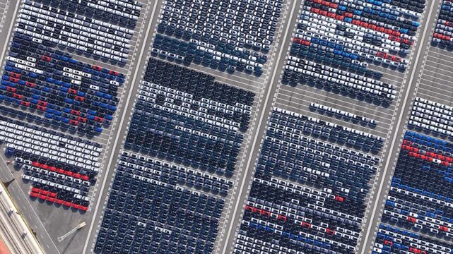 Aerial top‑down view of massive new car storage lot with neatly arranged vehicles	