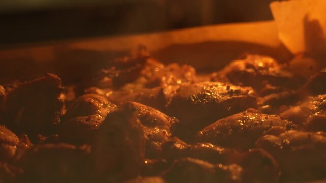 Close-up of chicken thighs with crispy skin being cooked in the oven. The murmur of chicken thighs in a hot oven.