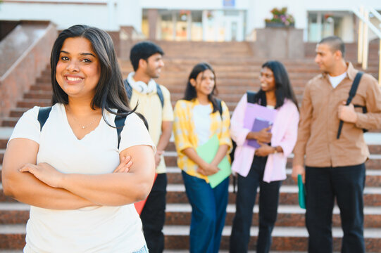Smiling indian student standing with friends on campus