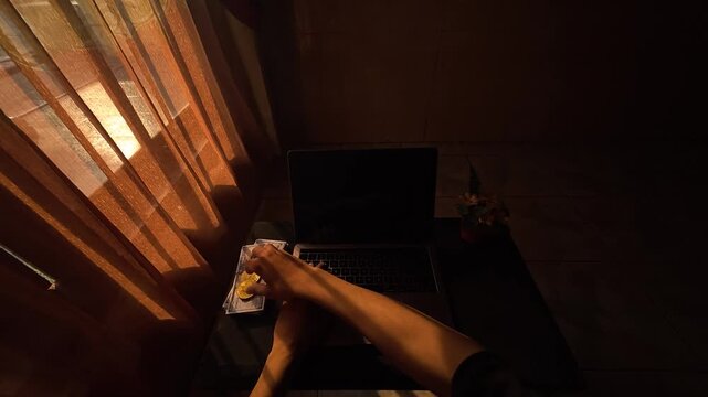 POV of stretching arms and flipping a metal token on a laptop desk in warm morning sunlight, slow motion 4K 120fps.