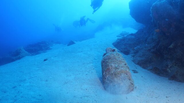 scuba divers are exploring antic old amphoras underwater
