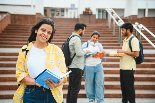 Smiling indian student standing on university campus