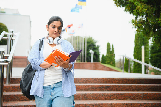 Indian student reading book walking on university campus