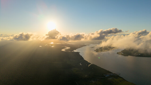 Aerial view of Ilha da Cotinga surrounded by the winding river and lush vegetation under a golden sunset sky in Paranagua, Parana, Brazil.