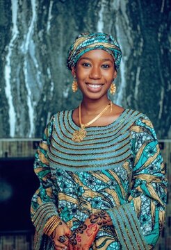 Portrait of a Smiling African Woman in Traditional Teal Ankara Dress with Headwrap and Henna