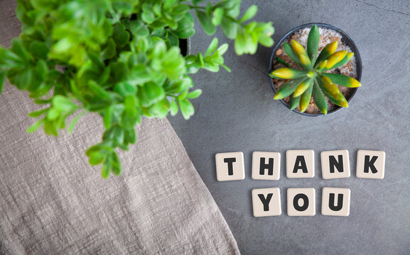 Thank You Text Spelled with Wooden Tiles on Concrete Surface