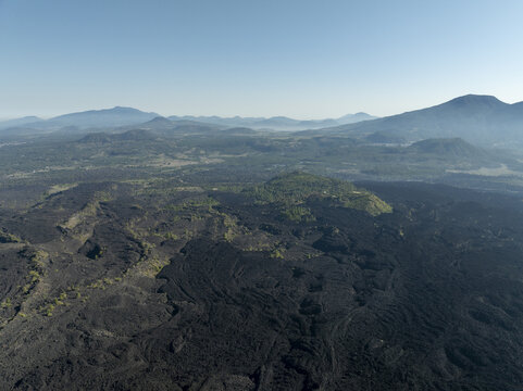 Aerial view of Paricutin volcano showing vast solidified lava fields, volcanic terrain, and distant mountains in San Juan Parangaricutiro, Michoacan, Mexico.