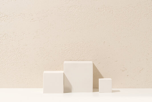 White Cube Podiums of Different Heights on White Shelf Against Travertine Wall Background