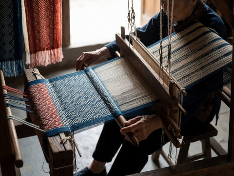 Elderly Asian Woman Weaving Traditional Textile on Wooden Loom