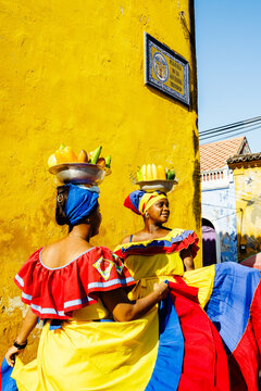 Palenqueras resting by a yellow colonial wall, Cartagena, Colombia