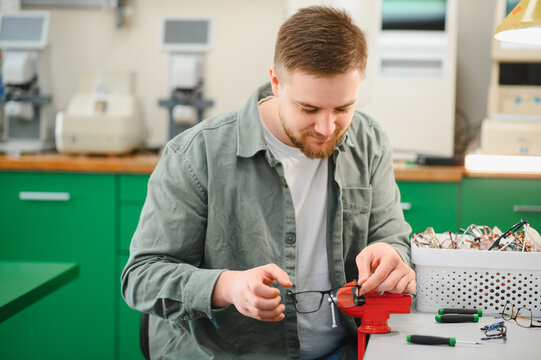Optician repairing eyeglasses on workbench in workshop