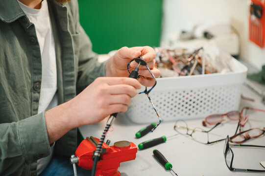 Optician repairing broken eyeglasses frame in workshop