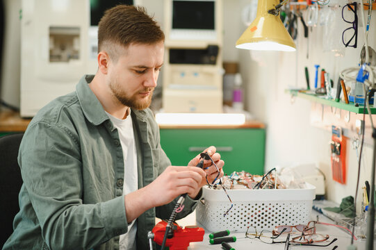 Optician technician repairing eyeglasses in optical workshop