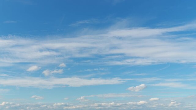 Beautiful abstract background featuring thin wispy cirrus clouds drifting across a bright blue sky in a cinematic timelapse motion with soft natural lighting and airy atmosphere
