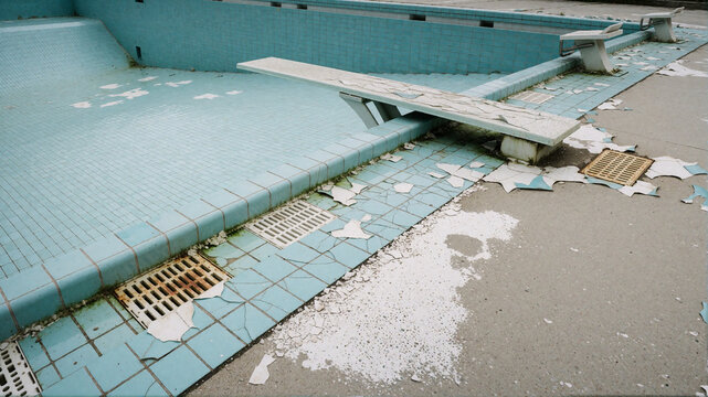 Abandoned swimming pool with broken tiles and diving boards
