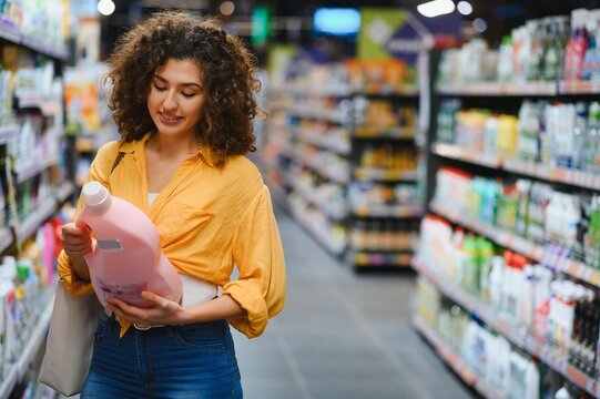 Woman buying laundry detergent in supermarket aisle