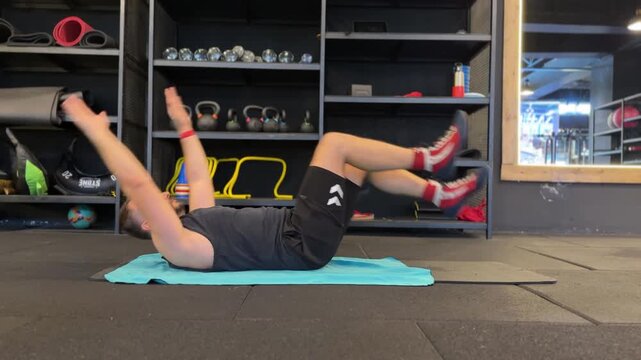 A detailed video of an athletic man performing the dead bug core exercise on the gym floor, demonstrating abdominal stability, coordinated limb movement, and proper fitness technique.