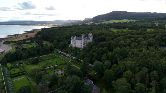 Drone shot over Dunrobin Castle estate in Golspie featuring fairytale conical spires, Victorian style parterre gardens, and North Sea coastal scenery in Sutherland Scotland