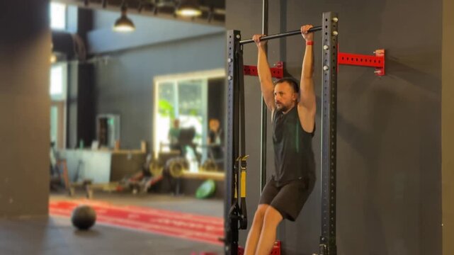 A dynamic video of an athletic man performing hanging leg raises in a modern gym, demonstrating strong core engagement, lower abdominal focus, and disciplined fitness training.