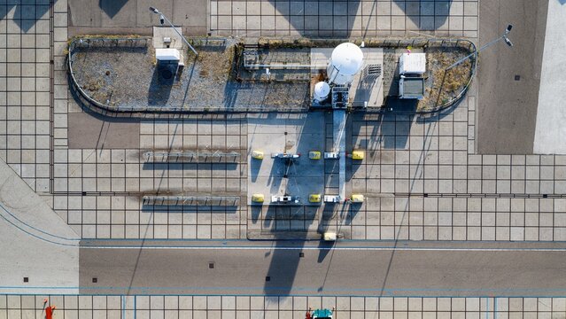 Aerial view of an industrial utility site with white storage tanks and concrete paving in Delft, South Holland, Netherlands.