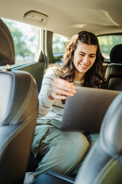 Woman working remotely with laptop in car backseat