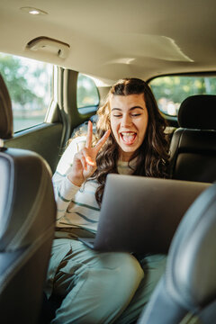 Young woman on video call showing peace sign in car