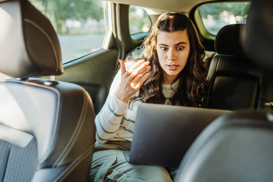 Woman reacting with frustration to laptop in car backseat
