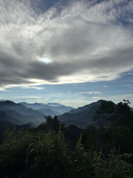 Dramatic cloudy sky over rolling green mountain ridges and foggy valley