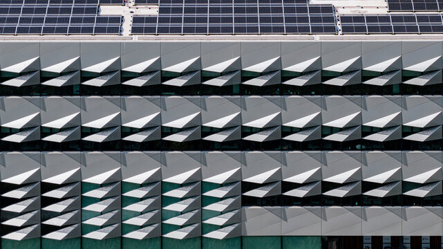 Aerial view of a modern building facade featuring geometric architectural panels and rooftop solar panels in Delft, South Holland, Netherlands.
