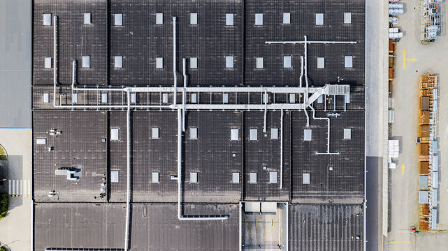 Aerial view of a large industrial warehouse roof with ventilation ducts, skylights, and a loading area in Delft, South Holland, Netherlands.