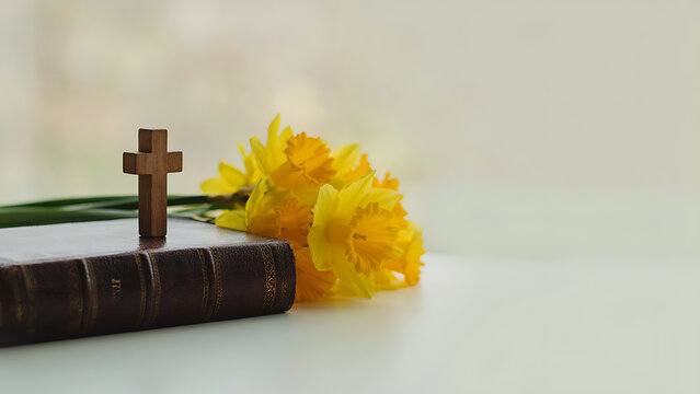 Christian cross on closed Bible beside yellow daffodils Easter concept