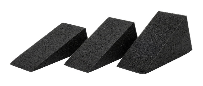 Black foam wedge block set isolated on dark background for minimalist product display mockup stage, geometric studio presentation platform, acoustic soundproofing absorption panel.