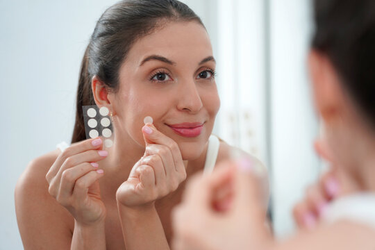 Close-up of Young Woman Applying Acne Treatment Anti-Pimple Patch on Face