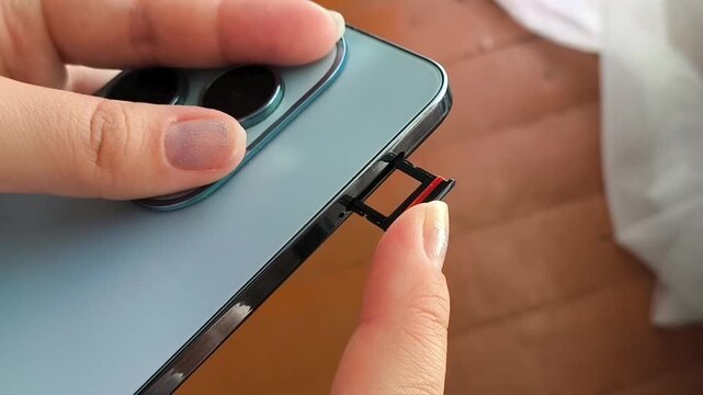 Woman putting SIM card into phone, SIM card installation, mobile data, network connection and telecommunications concept.