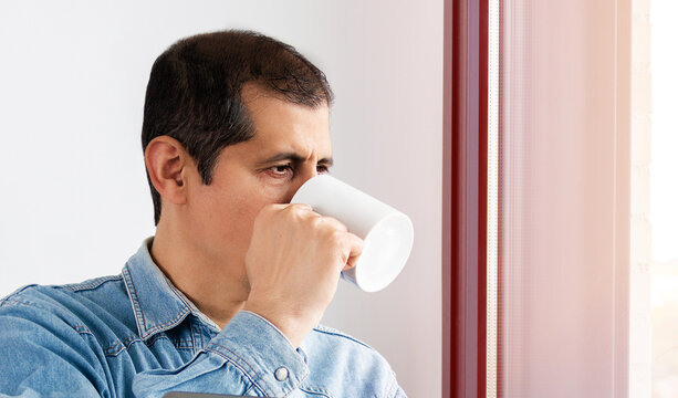 Cropped shot of a businessman while drinking coffee and looking out of the office window
