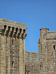 Stone castle walls, battlements, machicolations, and turrets under a clear blue sky © ann_lsnk
