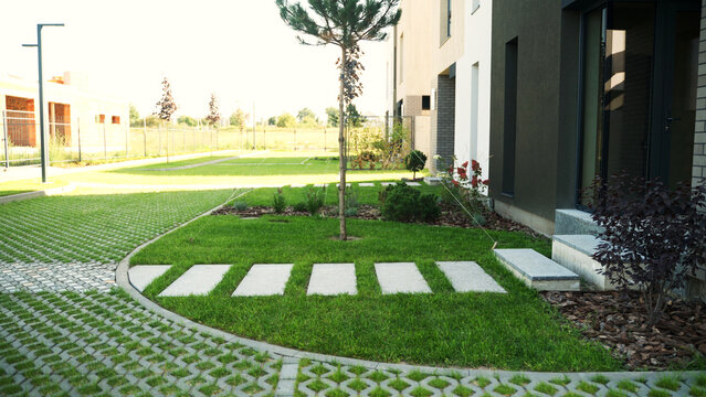 Contemporary house exterior with green lawn, stepping stones, and eco-friendly permeable paving for residential yard