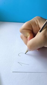 Teacher writing numbers with pen on paper during mathematics lesson, learning numbers, basic math and education concept.