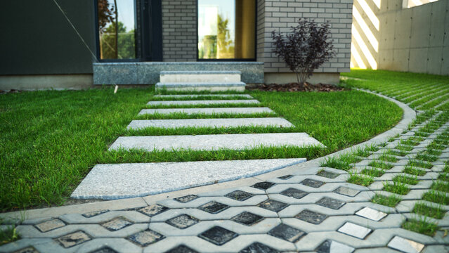 Modern house entrance with concrete stepping path and eco-friendly permeable paving system in a green lawn