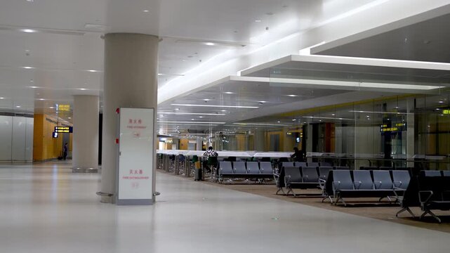 An empty modern indoor waiting area in an airport terminal, with rows of seats and smooth flooring.