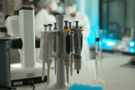 Micropipettes on Stand in Pharmaceutical Research Laboratory with Scientist in Background
