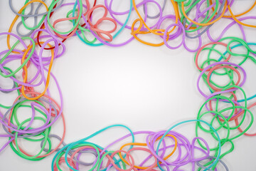 Fototapeta premium Colorful rubber bands forming a frame on a white background with copy space.
