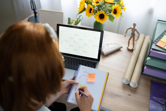 A white woman organizes her schedule from a laptop calendar