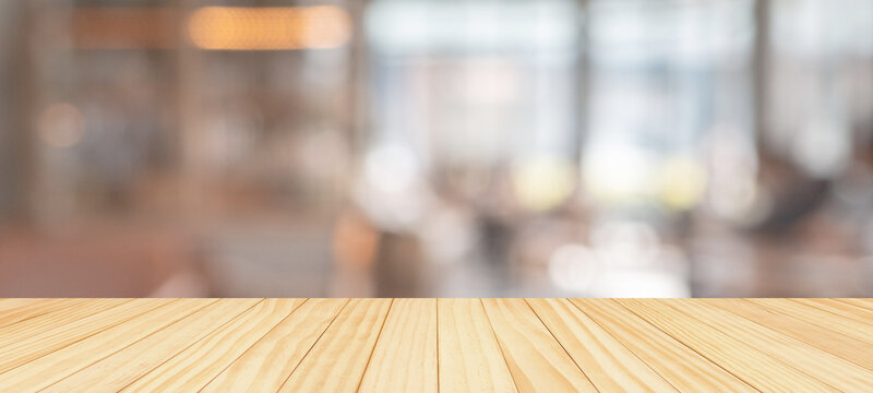 Wood table top with blurred coffee shop restaurant background with warm bokeh lights for product presentation