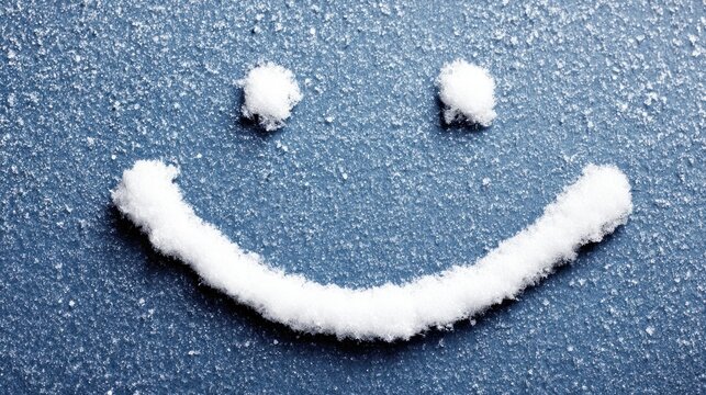 Smiling face drawn in snow on a frosty blue surface, symbolizing happiness and winter joy