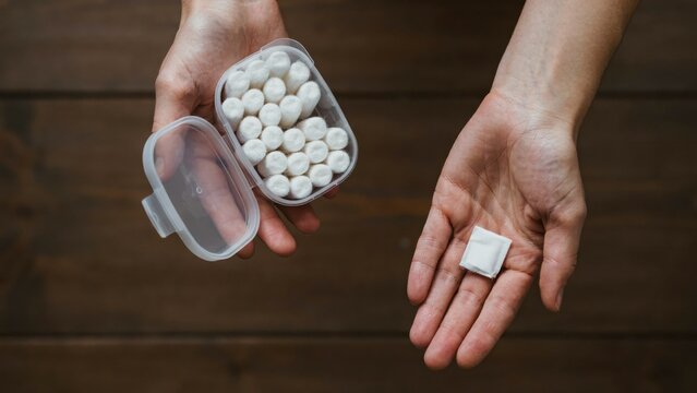 Hands holding nicotine pouches and container