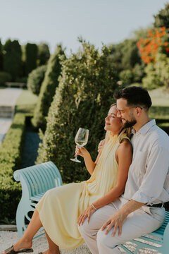 Couple enjoys a sunny afternoon in a beautiful garden sipping wine