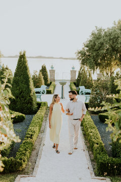 Couple enjoys a warm evening stroll through a beautiful garden by the water