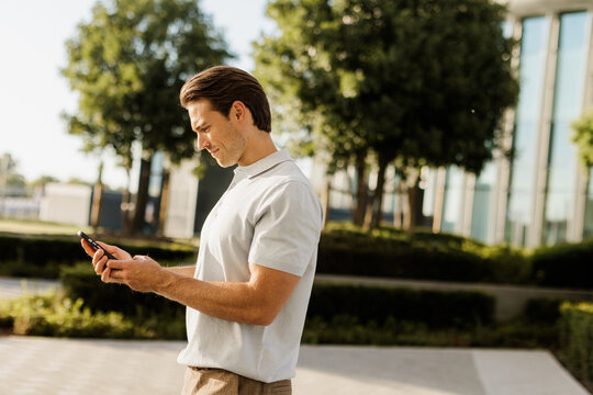 Man enjoying a sunny day while checking his phone in a modern park